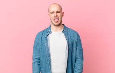 Kel adam tiksinti ve tedirginlik duyuyor, dilini dışarı çıkarıyor, iğrenç ve iğrenç bir şeyden hoşlanmıyor.