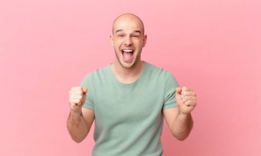 Kel adam şaşkın, heyecanlı ve mutlu hissediyor, gülüyor ve başarıyı kutluyor,!