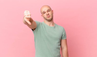 Kel bir adam kızgın, sinirli, hayal kırıklığına uğramış ya da canı sıkkın, ciddi bir bakışla başparmağını kaldırıyor.