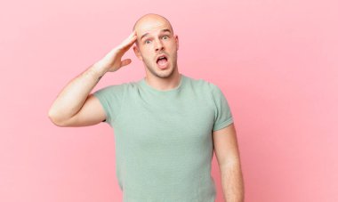 Kel adam mutlu, şaşkın ve şaşırmış görünüyor, gülümsüyor ve inanılmaz ve inanılmaz iyi haberleri fark ediyor.