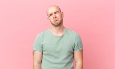 Kel bir adam üzgün ve mızmızlanıyor. Mutsuz bir bakışla, olumsuz ve hayal kırıklığına uğramış bir tavırla ağlıyor.