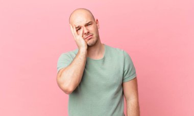 Kel bir adam yorgun, sıkıcı ve can sıkıcı bir işten sonra sıkılmış, hayal kırıklığına uğramış ve uykulu hisseder.