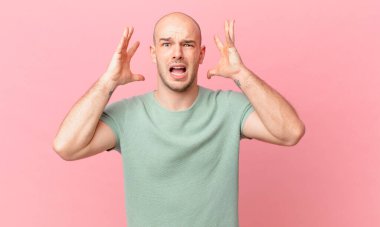 Kel adam elleri havada bağırıyor, öfkeli, sinirli, stresli ve üzgün hissediyor.