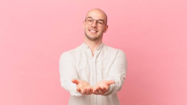 Dost canlısı, kendine güvenen, olumlu bakışlı, bir nesne ya da konsept sunan ve gösteren kel bir adam.