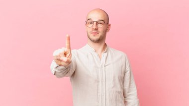 Kel adam gururla gülümsüyor ve gururla bir numaralı pozunu veriyor, kendini lider gibi hissediyor.