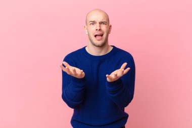 Kel adam umutsuz ve sinirli görünüyor, stresli, mutsuz ve sinirli, bağırıyor ve çığlık atıyor.