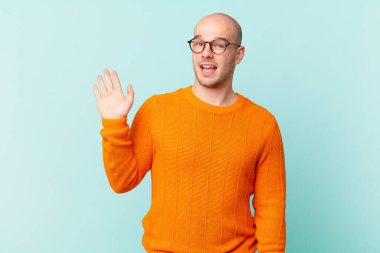 Kel adam mutlu ve neşeyle gülümsüyor, el sallıyor, seni selamlıyor ve selamlıyor, ya da hoşça kal diyor.