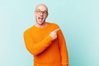 Kel adam heyecanlı ve şaşırmış görünüyor. Yana ve yukarıya bakıp boşluğu kopyalıyor.