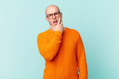 Kel bir adam ağzı ve gözleri sonuna kadar açık ve eli çenesinde, nahoş bir şekilde şokta, ne söylüyor ya da vay be