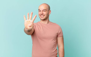 Kel adam gülümsüyor ve arkadaş canlısı görünüyor, 4 ya da 4 numarayı gösteriyor, eli önde, geriye doğru sayıyor.