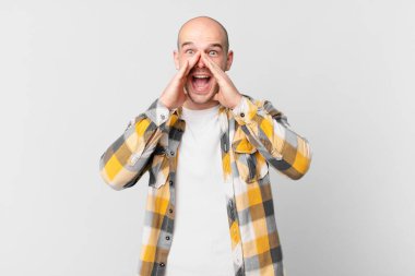 Kel adam mutlu, heyecanlı ve pozitif hissediyor. Elleri ağızda, bağırarak bağırıyor.