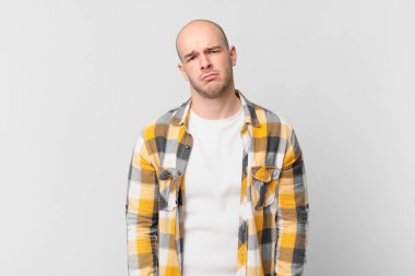 Kel bir adam üzgün ve mızmızlanıyor. Mutsuz bir bakışla, olumsuz ve hayal kırıklığına uğramış bir tavırla ağlıyor.