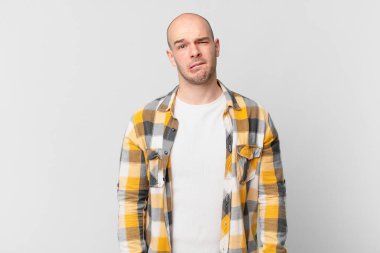 Kafası karışmış, kafası karışmış, sinirsel bir hareketle dudağını ısıran, sorunun cevabını bilmeyen kel bir adam.