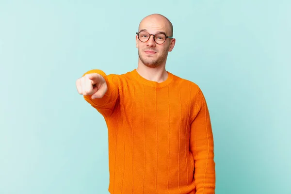 bald man pointing at camera with a satisfied, confident, friendly smile, choosing you