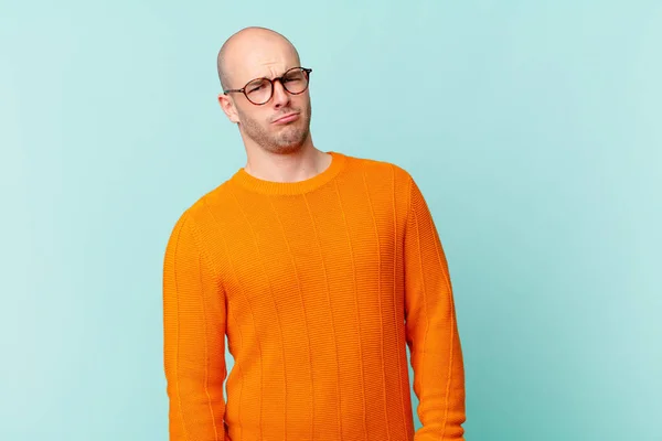 bald man feeling sad, upset or angry and looking to the side with a negative attitude, frowning in disagreement