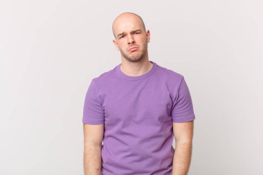 Kel bir adam üzgün ve mızmızlanıyor. Mutsuz bir bakışla, olumsuz ve hayal kırıklığına uğramış bir tavırla ağlıyor.