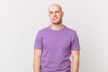 Kafası karışmış, kafası karışmış, sinirsel bir hareketle dudağını ısıran, sorunun cevabını bilmeyen kel bir adam.