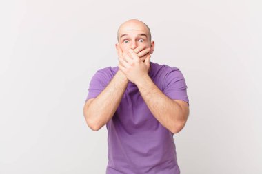 Kel adam elleri ile ağzını kapatıyor, şok olmuş, şaşırmış bir ifadeyle, sır saklıyor ya da 