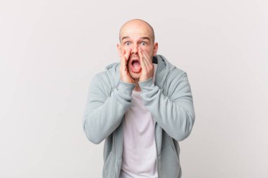 Kel adam şok olmuş ve korkmuş hissediyor, ağzı açık ve elleri yanaklarında korkmuş görünüyor.