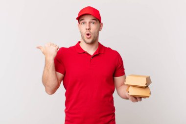 İnançsızlıktan şaşkın şaşkın bakıyor, yan taraftaki objeyi işaret ediyor ve 