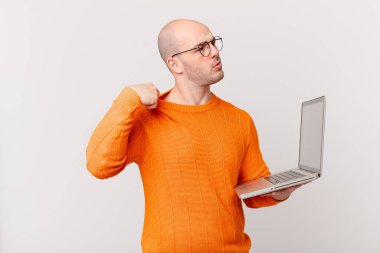 Bilgisayarı olan kel bir adam stresli, endişeli, yorgun ve hayal kırıklığına uğramış, gömleğini çekiştirmiş, sorunlu görünüyor.