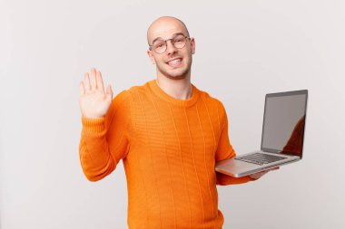 Bilgisayarlı kel adam mutlu ve neşeli bir şekilde gülümsüyor, el sallıyor, seni selamlıyor ve selamlıyor, ya da elveda diyor.