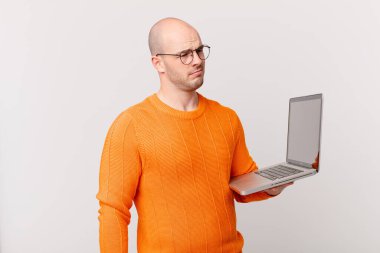 Bilgisayarlı kel bir adam üzgün, üzgün ya da kızgın ve olumsuz bir tavır takınıyor, anlaşmazlık içinde kaşlarını çatıyor.