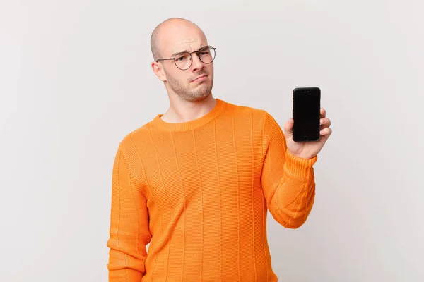 Łysy Mężczyzna Smartfonem Smutny Zdenerwowany Lub Zły Patrząc Bok Negatywnym — Zdjęcie stockowe