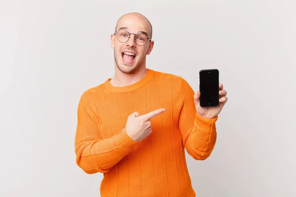 Homem Careca Com Smartphone Olhando Animado Surpreso Apontando Para Lado — Fotografia de Stock