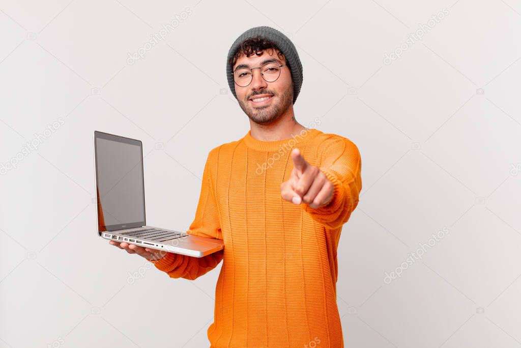 nerd man with computer pointing at camera with a satisfied, confident, friendly smile, choosing you