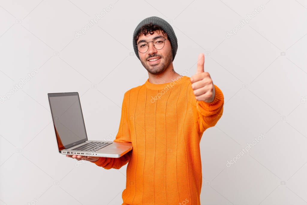 nerd man with computer feeling proud, carefree, confident and happy, smiling positively with thumbs up