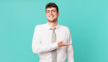 Genç işadamı mutlu bir şekilde gülümsüyor, mutlu hissediyor ve fotokopi alanında bir konsept gösteriyor.