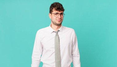 Genç işadamı üzgün, üzgün ya da kızgın hissediyor ve olumsuz bir tavırla, anlaşmazlık içinde somurtuyor.