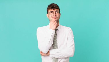 Genç işadamı düşünüyor, kuşkulu ve şaşkın hissediyor, farklı seçeneklerle, hangi kararı vereceğini merak ediyor.