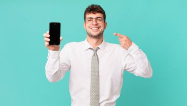 Akıllı telefonlu bir iş. Kendine güvenen bir gülümseme. Geniş bir gülümseme, pozitif, rahat ve tatmin edici bir tavır.