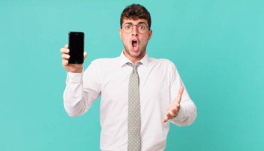 Akıllı telefonlu bir iş, ağzı açık ve şaşkın, şaşkın ve hayret verici inanılmaz bir sürprizle