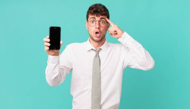 Akıllı telefonlu bir iş. Şaşırmış, ağzı açık, şok olmuş, yeni bir düşünce, fikir ya da konsept keşfediyor.