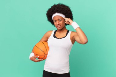 Afro kadın şaşkın ve şaşkın hissediyor, deli, deli ya da aklını kaçırmış olduğunu gösteriyor. Basketbol konsepti