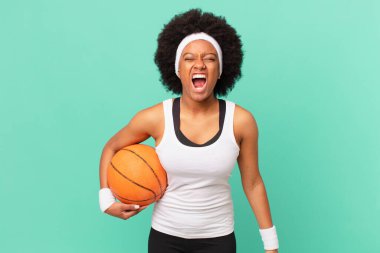 Afro kadın agresif bir şekilde bağırıyor, kızgın, sinirli, öfkeli ya da sinirli görünüyor, hayır diye bağırıyor. Basketbol konsepti