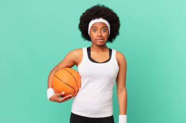 Afro kadın şaşkın ve şaşkın görünüyor, gergin bir hareketle dudağını ısırıyor, sorunun cevabını bilmiyor. Basketbol konsepti