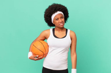 afro woman feeling puzzled and confused, with a dumb, stunned expression looking at something unexpected. basketball concept