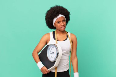 afro woman feeling puzzled and confused, with a dumb, stunned expression looking at something unexpected diet concept
