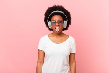 Afro kadın iğrenmiş ve rahatsız olmuş hissediyor, dilini dışarı çıkarıyor, iğrenç ve iğrenç bir şeyden hoşlanmıyor. müzik konsepti