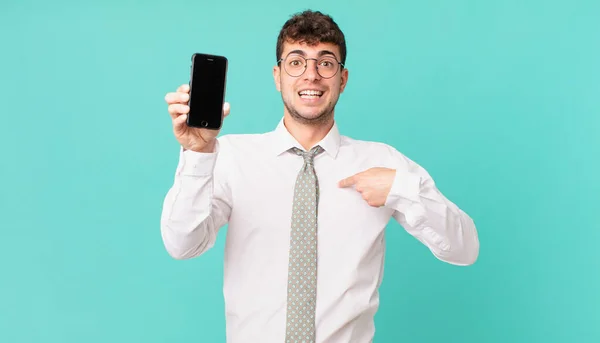 スマートフォンを手にしたビジネスは幸せと驚きと誇りを感じ 興奮と驚きの表情で自己を指差し — ストック写真