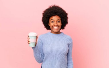 Afro kadın mutlu ve hoş bir şekilde şaşırmış görünüyor. Büyülenmiş ve şok olmuş bir ifadeyle heyecanlanıyor. kahve konsepti