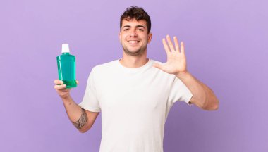 Gargarası olan adam gülümsüyor ve arkadaş canlısı görünüyor, 5 ya da 5 numarayı gösteriyor, eli önde, geriye doğru sayıyor.