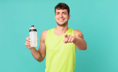 fitness adamı kameraya tatmin olmuş, kendinden emin, dostane bir gülümsemeyle bakıyor ve seni seçiyor.