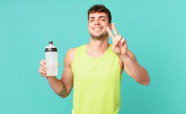 Fitness adamı gülümsüyor ve mutlu görünüyor, kaygısız ve pozitif, zafer ya da barışı simgeliyor.