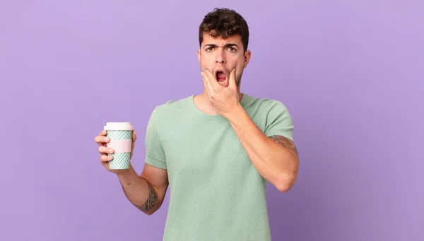 口と目を大きく開いて顎を手でコーヒーを飲む男何かすごいと言いながら — ストック写真