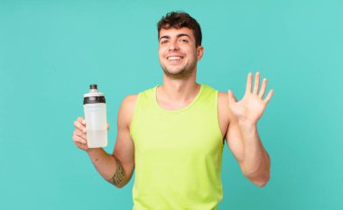 Fitness adamı mutlu ve mutlu bir şekilde gülümser, el sallar, seni karşılar ve selamlar, ya da elveda der.